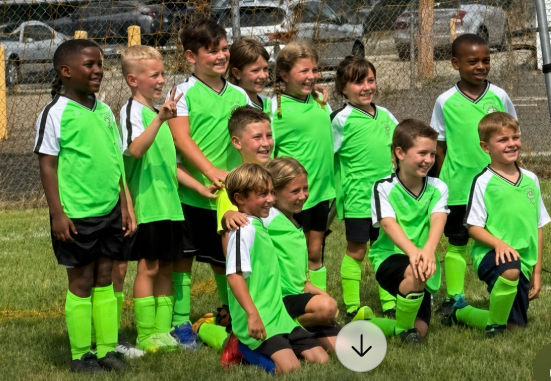 Children's soccer team smiling together in green uniforms